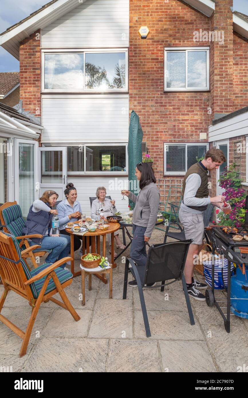 Una famiglia con tre generazioni che ha una famiglia BBQ a casa, Oxfordshire Inghilterra UK Foto Stock