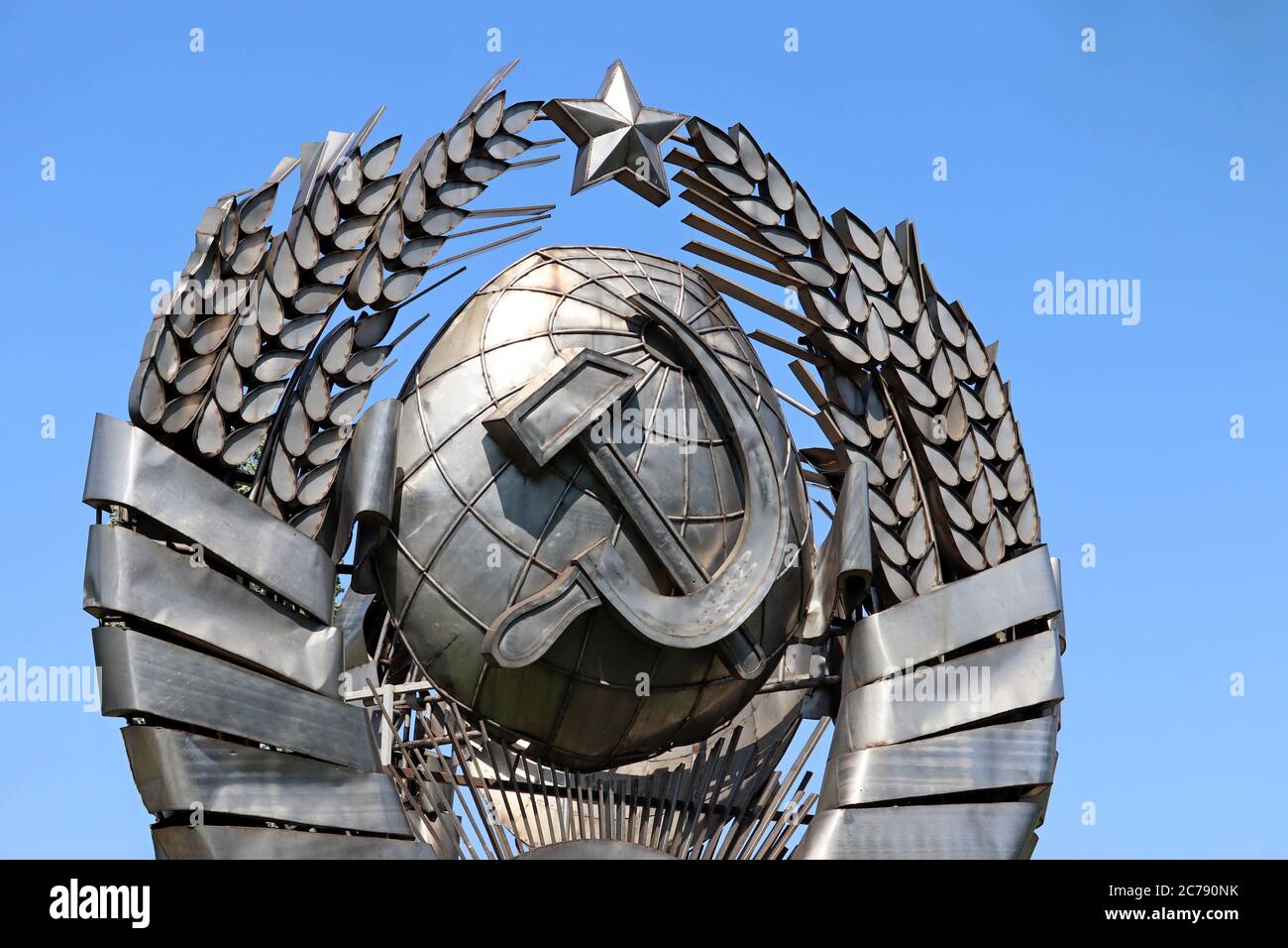 Stemma dell'URSS, simbolo comunista e socialista. Stemma sovietico metallico su sfondo blu del cielo Foto Stock