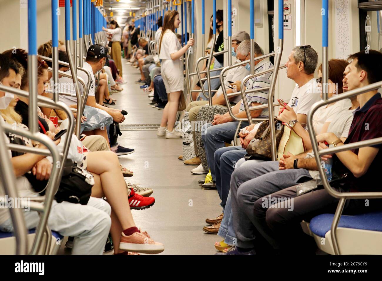 Folla di persone in treno in metropolitana in estate, i passeggeri senza maschere si siedono con smartphone. Interno della metropolitana durante l'epidemia di coronavirus Foto Stock