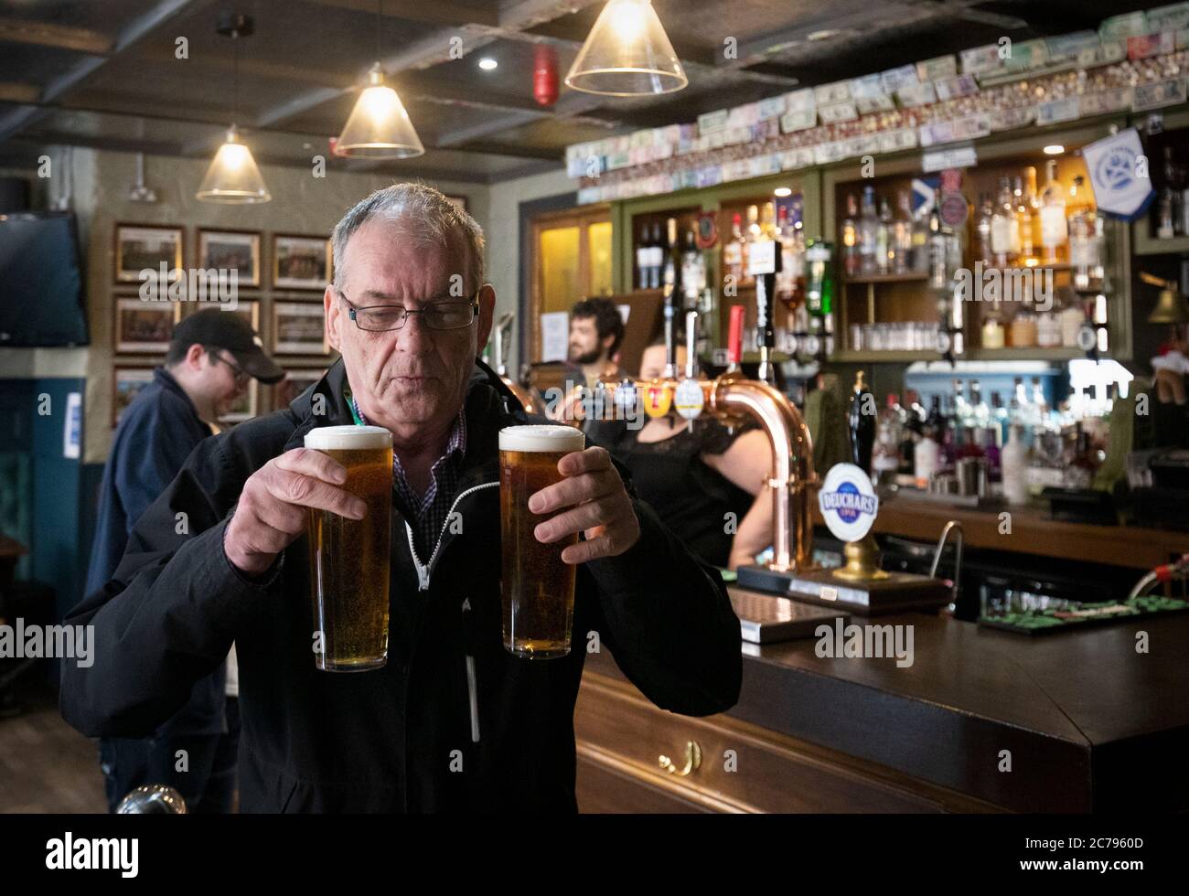 George McDonald, di Clemiston, è il primo cliente ad essere servito presso lo Scotsman's Lounge pub di Edimburgo, poiché pub, bar e ristoranti in tutta la Scozia hanno aperto aree interne per la prima volta da marzo dopo l'abolizione di ulteriori restrizioni di blocco del coronavirus. Foto Stock