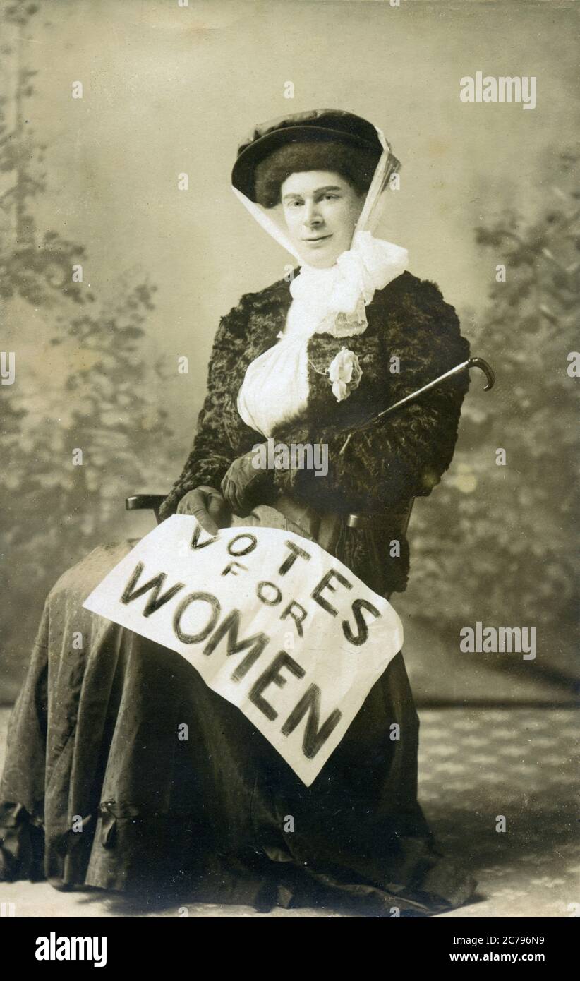 Suffragette seduta, 1910 cartolina di un'attivista per i voti per le donne con il poster drappeggiato sopra il suo grembo Foto Stock