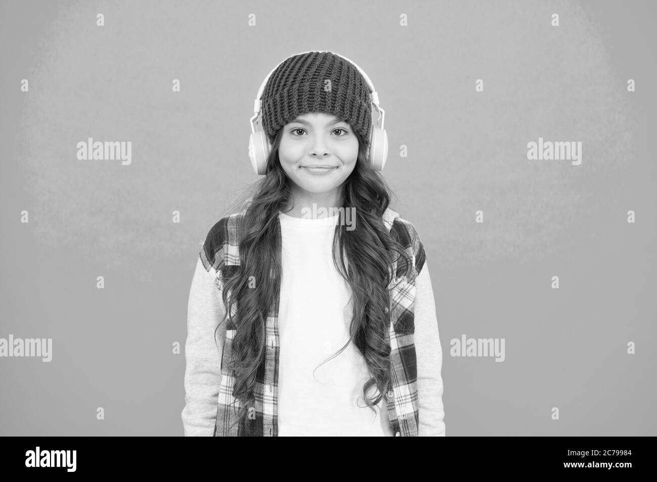 Sorridente adolescente ascoltare la musica nelle cuffie. ragazzino stile casual. autunno umore tune. piccolo bambino di capelli lunghi godono di stereo. infanzia felice. Felice hipster ragazza sfondo turchese. Foto Stock