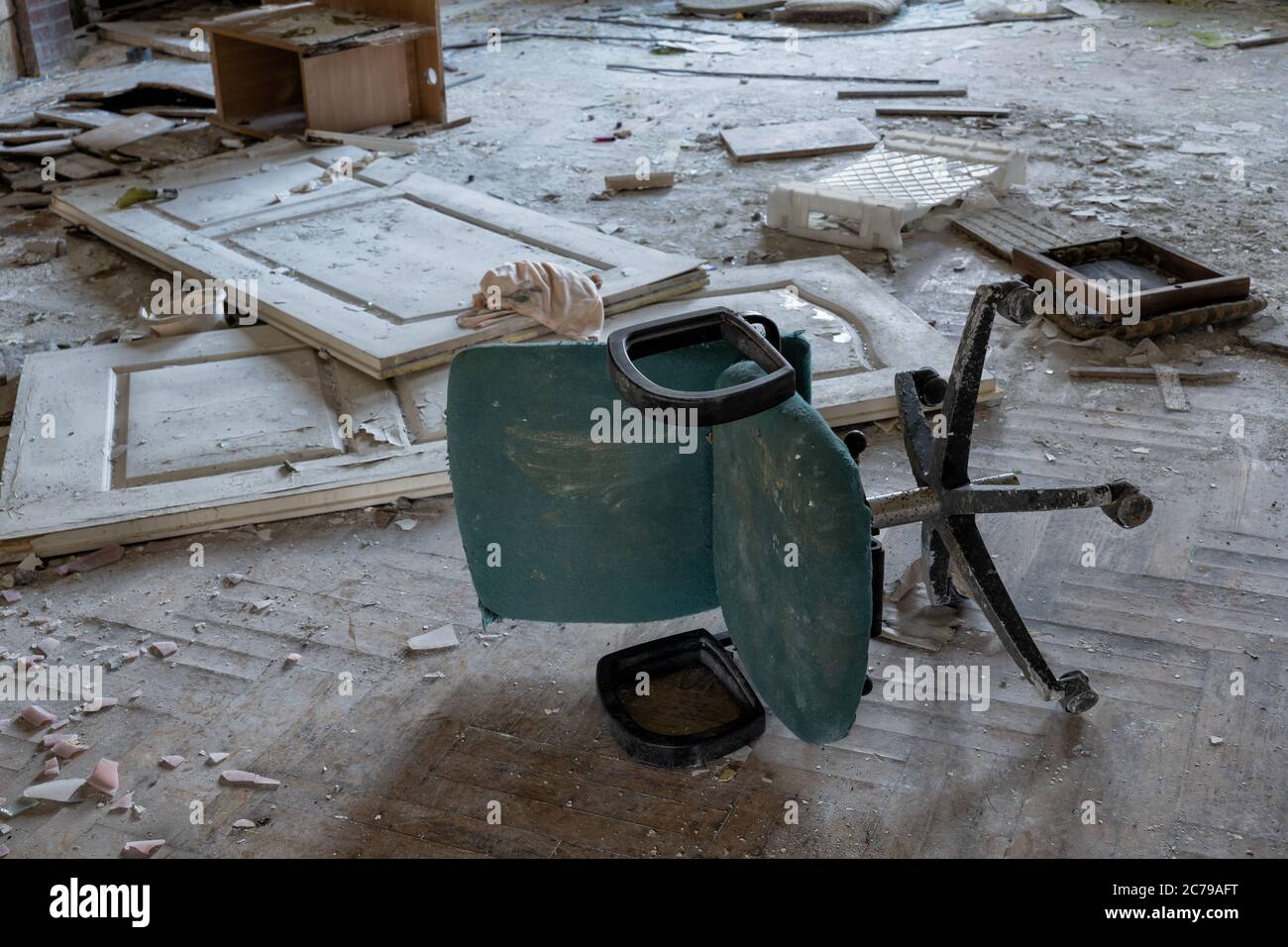 Sporco bussato sopra la sedia girevole dell'ufficio in un pavimento disordinato della stanza dell'edificio abbandonato Foto Stock