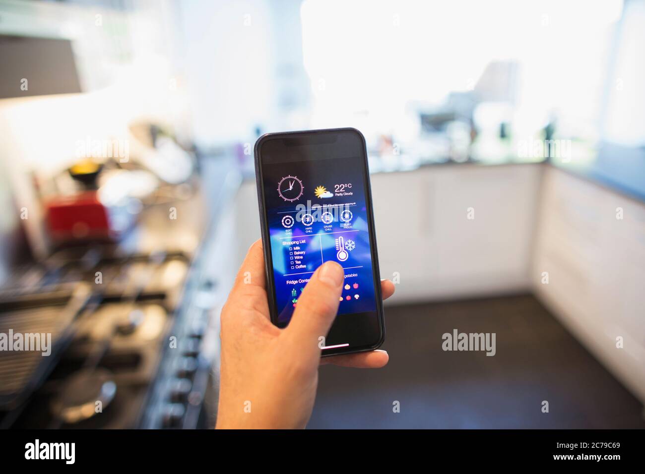 POV Man regolazione del controllo della climatizzazione dallo smartphone in cucina Foto Stock