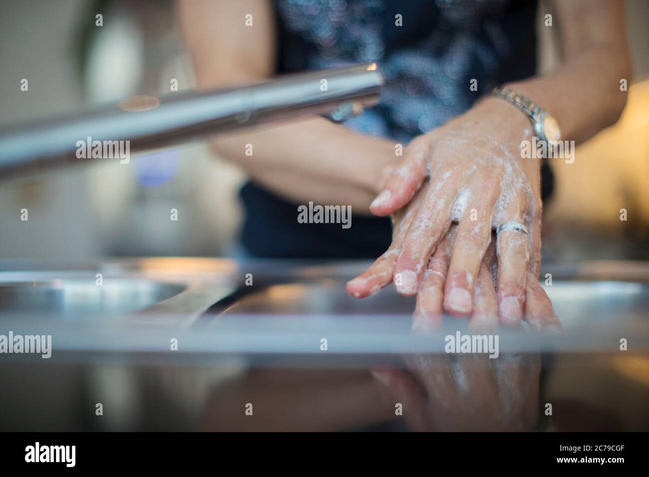 Chiudi donna lavando le mani con sapone al lavello della cucina Foto Stock