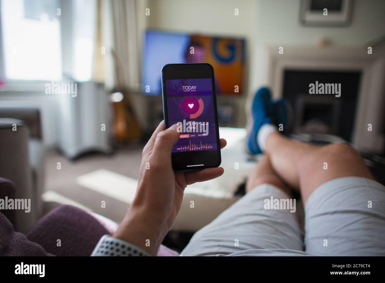 Uomo POV che controlla le statistiche di salute su smartphone in soggiorno Foto Stock