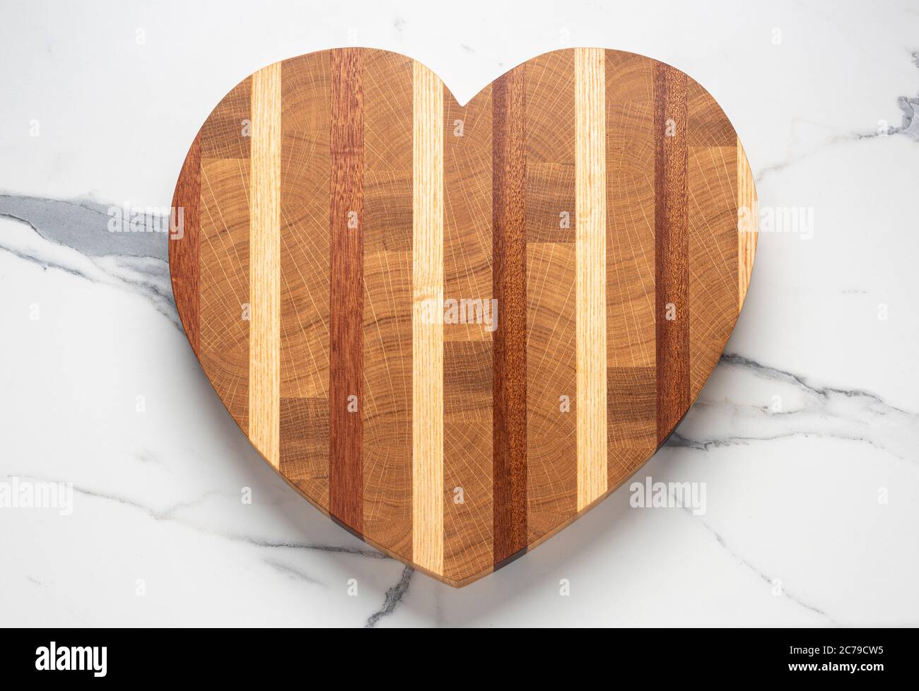 Tagliere in legno a forma di cuore sulla superficie in marmo Foto Stock