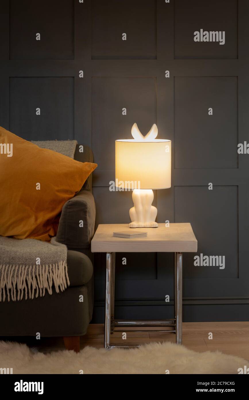 Lampada per orecchie di coniglio con bordo di divano e sfondo grigio pannellato Foto Stock