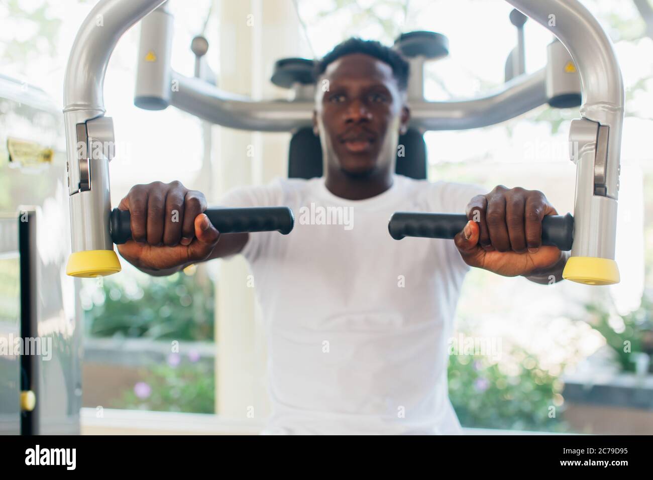 Atleta americano africano che fa l'esercitazione per i muscoli del petto sulla macchina del mazzo del pec durante l'allenamento nella palestra. Foto Stock