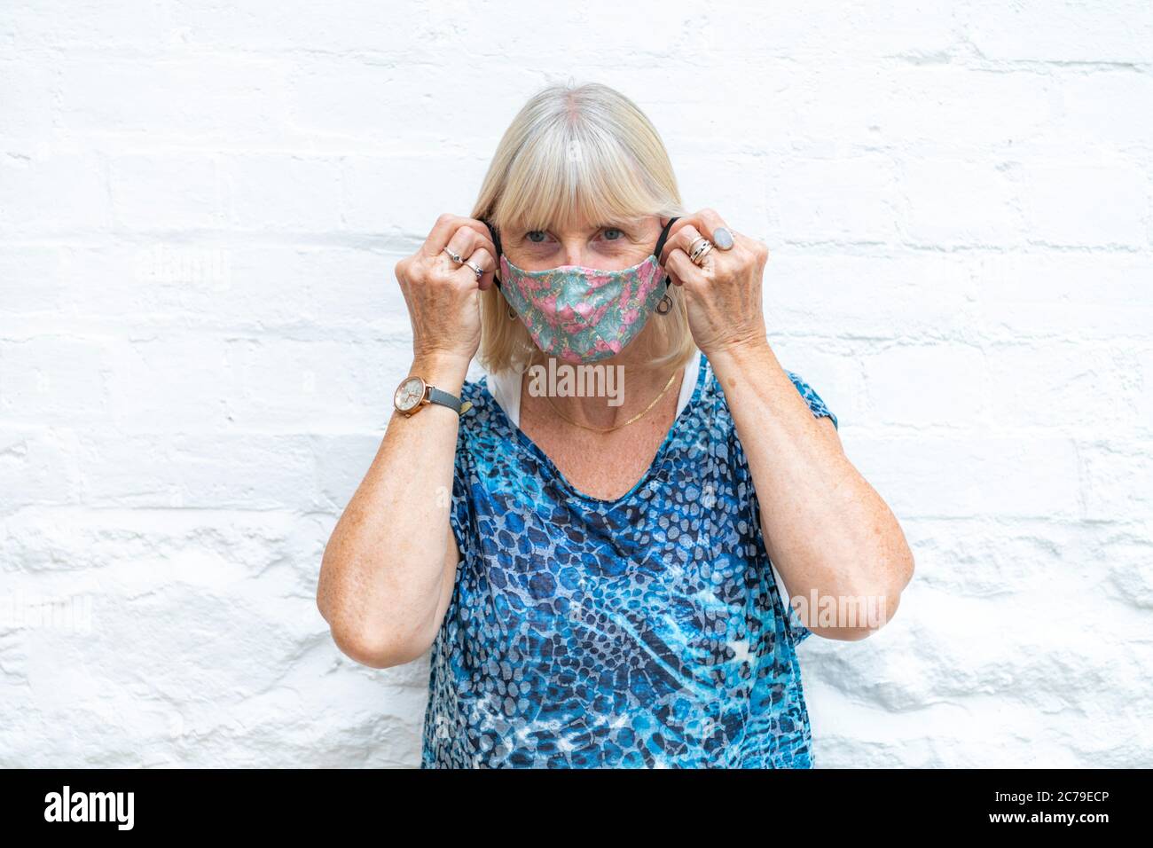 Donna che indossa una maschera facciale elegante e alla moda Coronavirus durante la pandemia Covid-19, pronta per la fine del blocco che va fuori in pubblico. Sfondo bianco Foto Stock