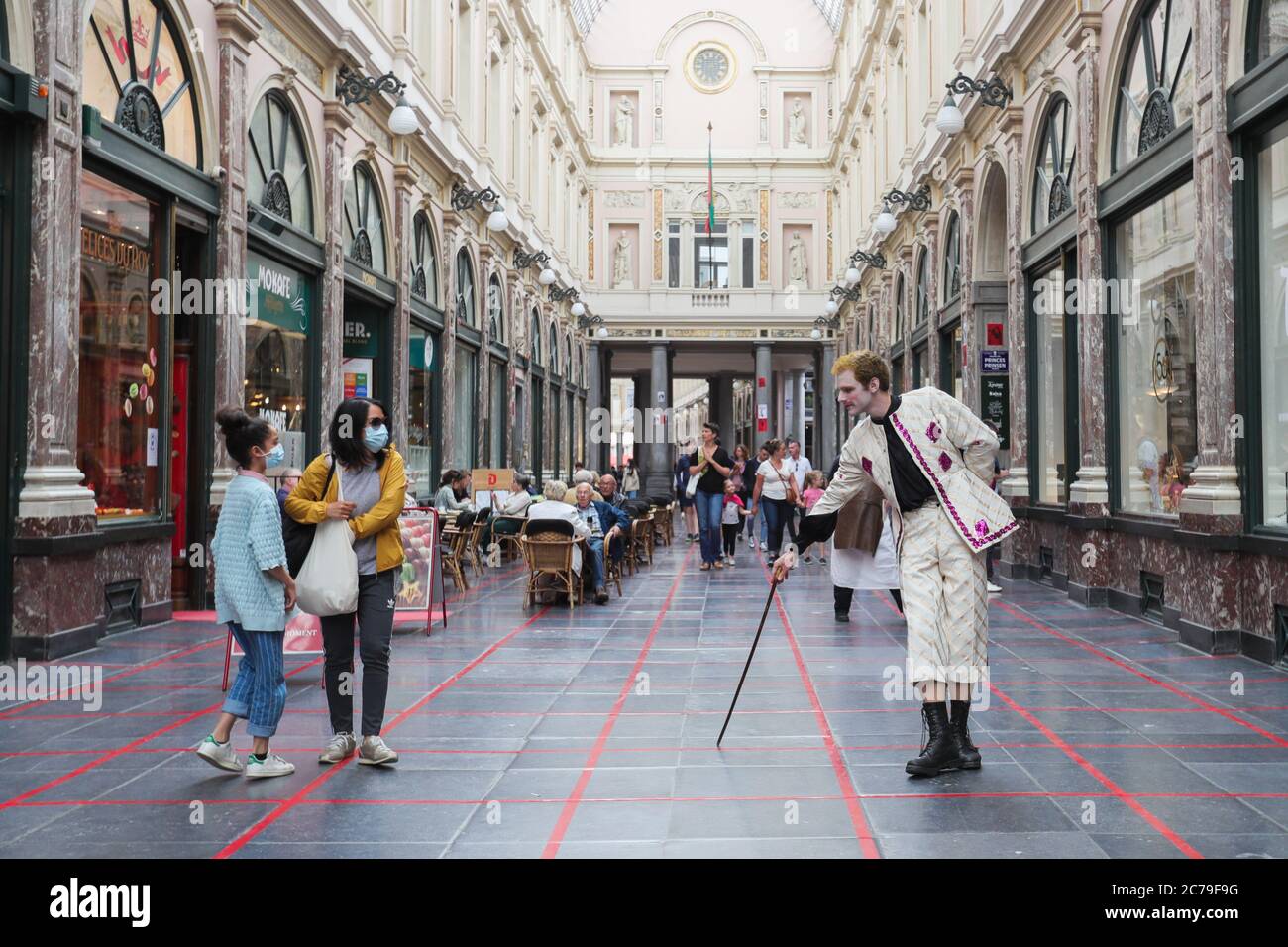 (200715) -- BRUXELLES, 15 luglio 2020 (Xinhua) -- un artista gioca una partita in griglia con i passanti alla Galleria reale di Saint Hubert a Bruxelles, Belgio, 15 luglio 2020. Mantenendo sempre uno spazio diverso dagli altri, gli artisti della troupe hanno recentemente iniziato a giocare con i passanti sulle griglie segnate a terra nel centro di Bruxelles. Il gioco è stato progettato per far rispettare le regole di distanza sociale durante la pandemia COVID-19. (Xinhua/Zheng Huansong) Foto Stock