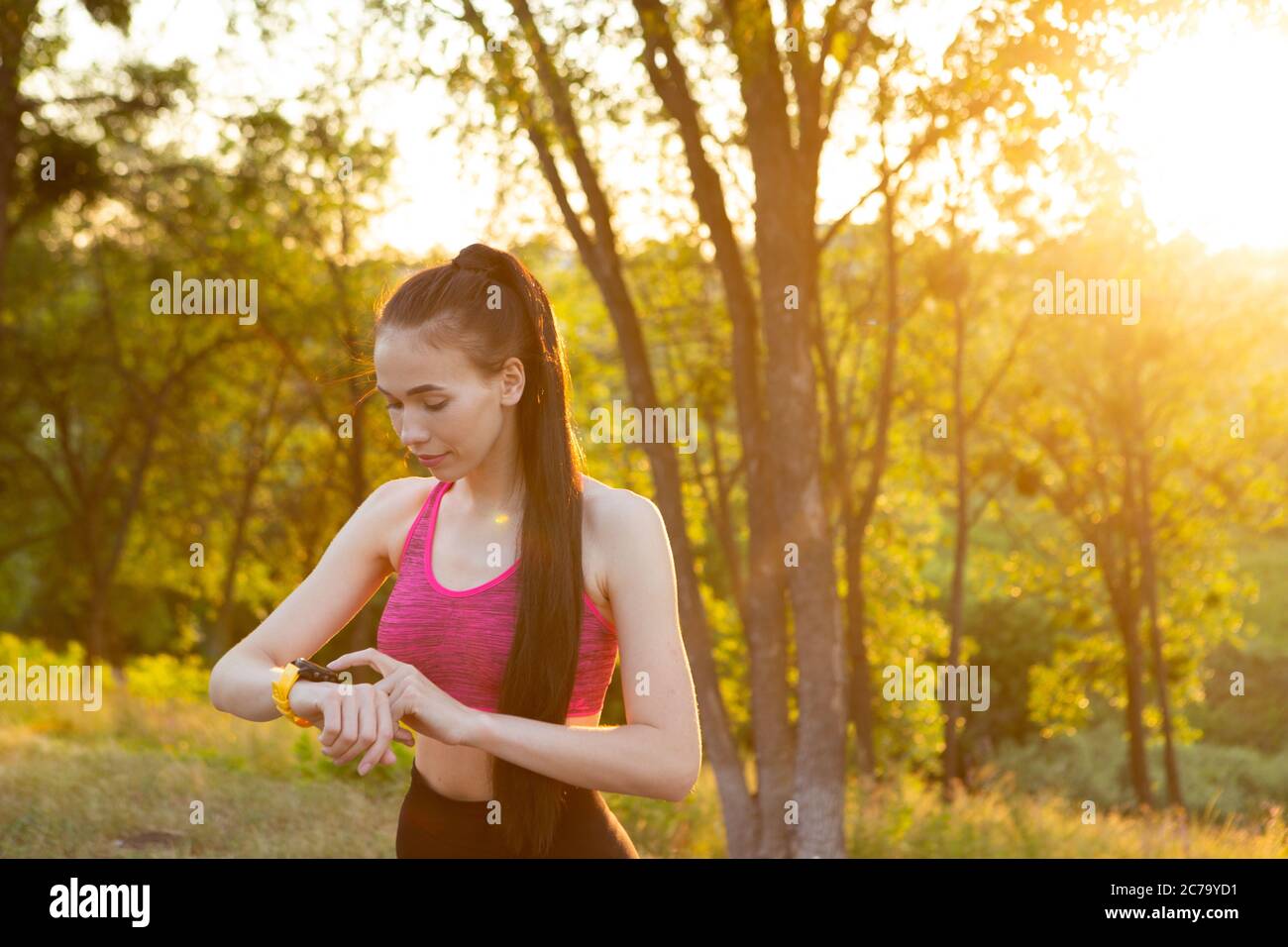 Donna che controlla il dispositivo indossabile per il monitoraggio della salute e del fitness nel parco. Foto Stock
