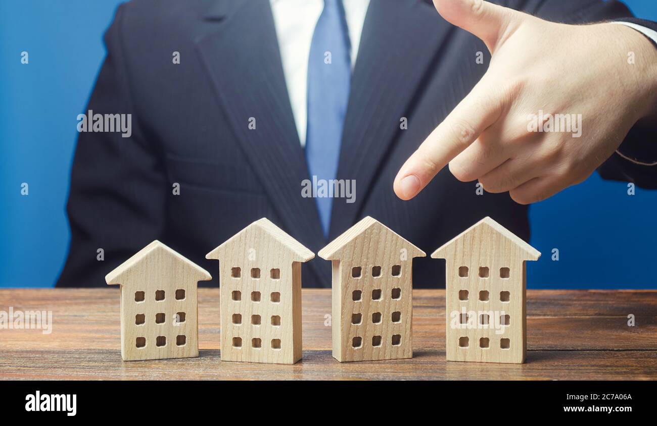 Un uomo sceglie una casa di appartamento tra molte opzioni di proposizioni nel mercato immobiliare. Soluzione di alloggiamento. Infrastrutture e infrastrutture. Investitori Foto Stock