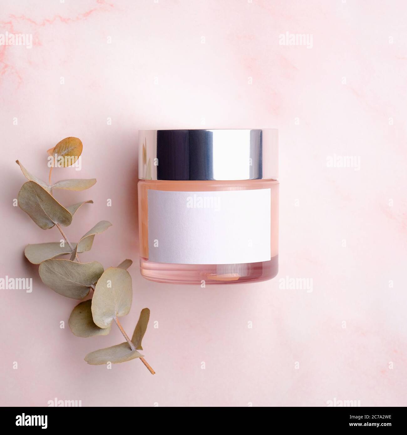 Vasetto con crema idratante e foglia di eucalipto su fondo rosa. Design dell'imballaggio di prodotti cosmetici, modello di contenitore Foto Stock