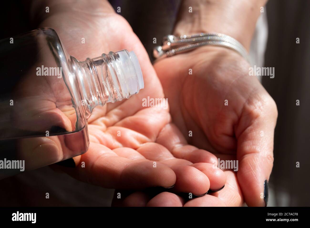 Primo piano bottiglia di colonia durante il travaso a mano contro il coronavirus. Foto Stock