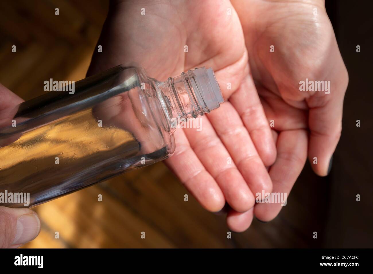 Primo piano bottiglia di colonia durante il travaso a mano contro il coronavirus. Foto Stock
