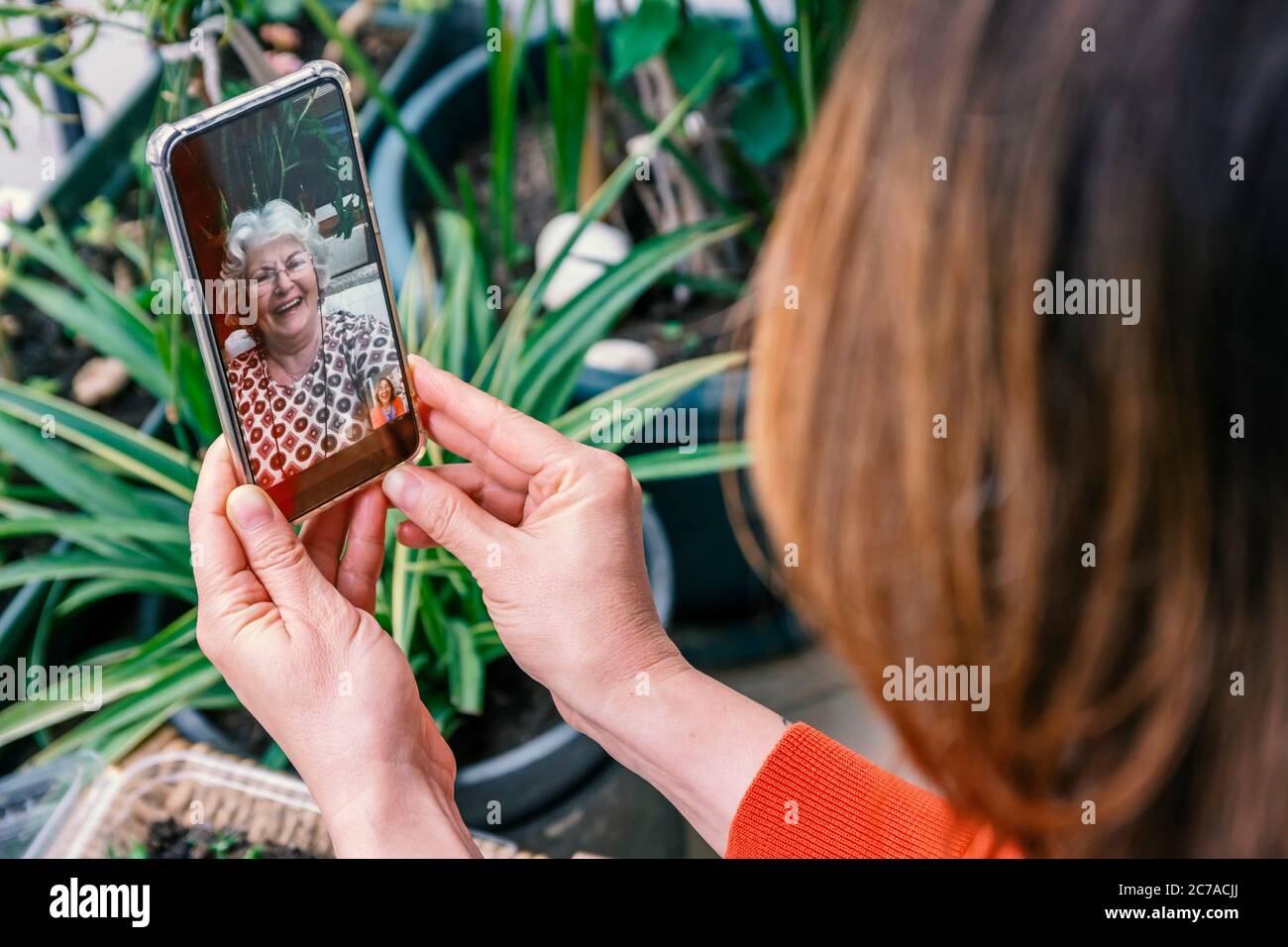 Giorno della madre o parlare con la madre in soggiorno a casa o nuovi concetti di giorni normali. Donna che parla con la madre tramite videochiamata a casa. Foto Stock