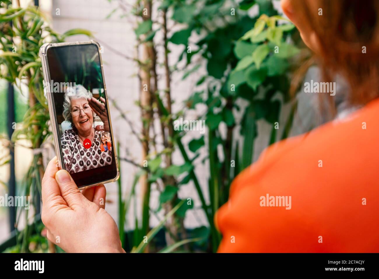 Giorno della madre o parlare con la madre in soggiorno a casa o nuovi concetti di giorni normali. Donna che parla con la madre tramite videochiamata a casa. Foto Stock