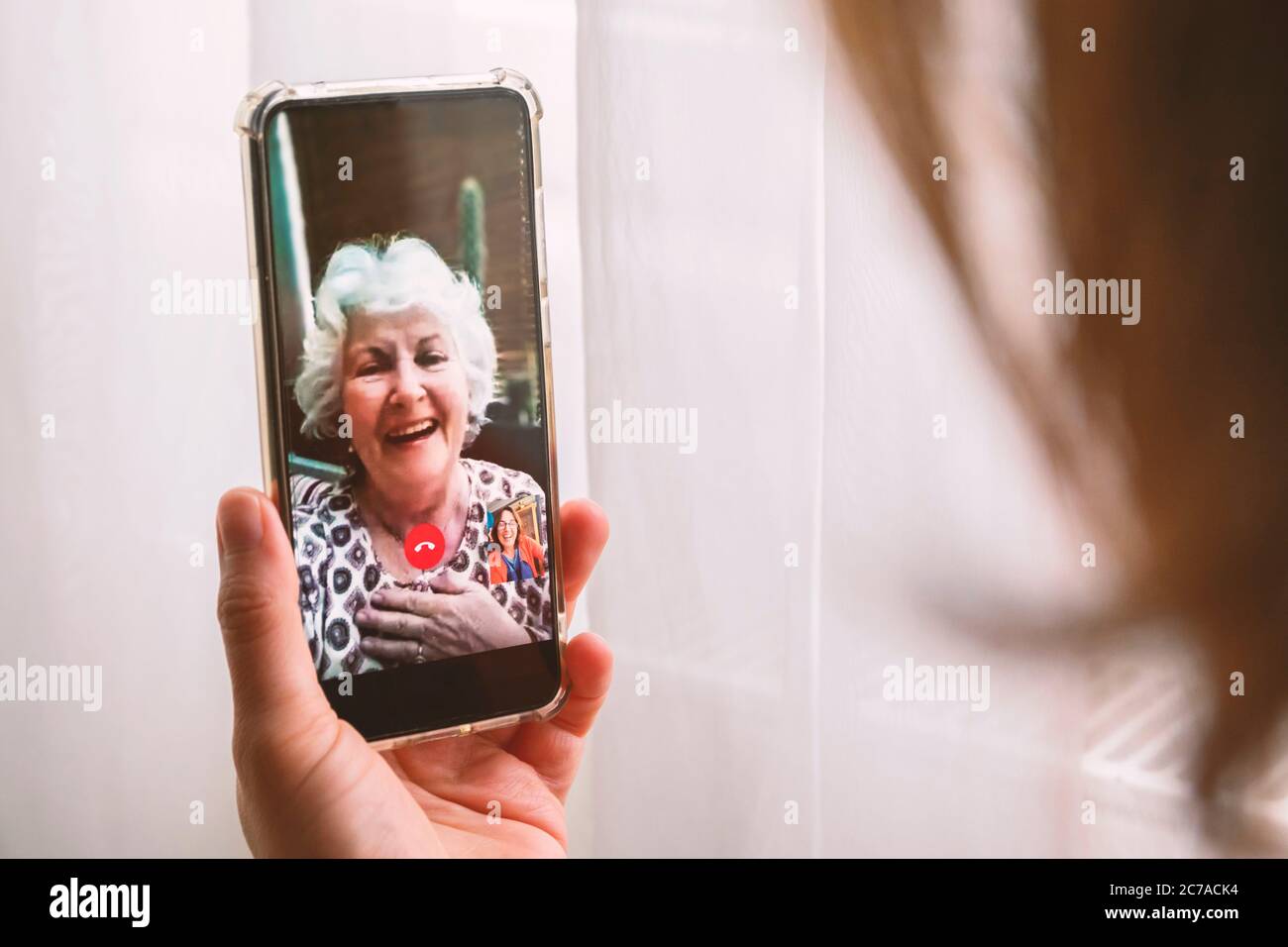 Giorno della madre o parlare con la madre in soggiorno a casa o nuovi concetti di giorni normali. Donna che parla con la madre tramite videochiamata a casa. Foto Stock