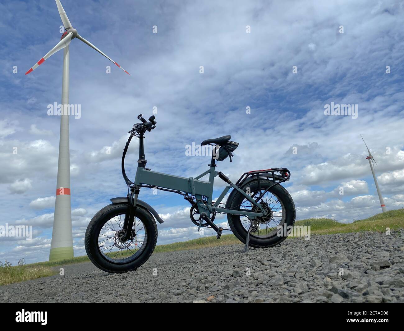 Moderna bicicletta elettrica con turbina eolica sullo sfondo Foto Stock