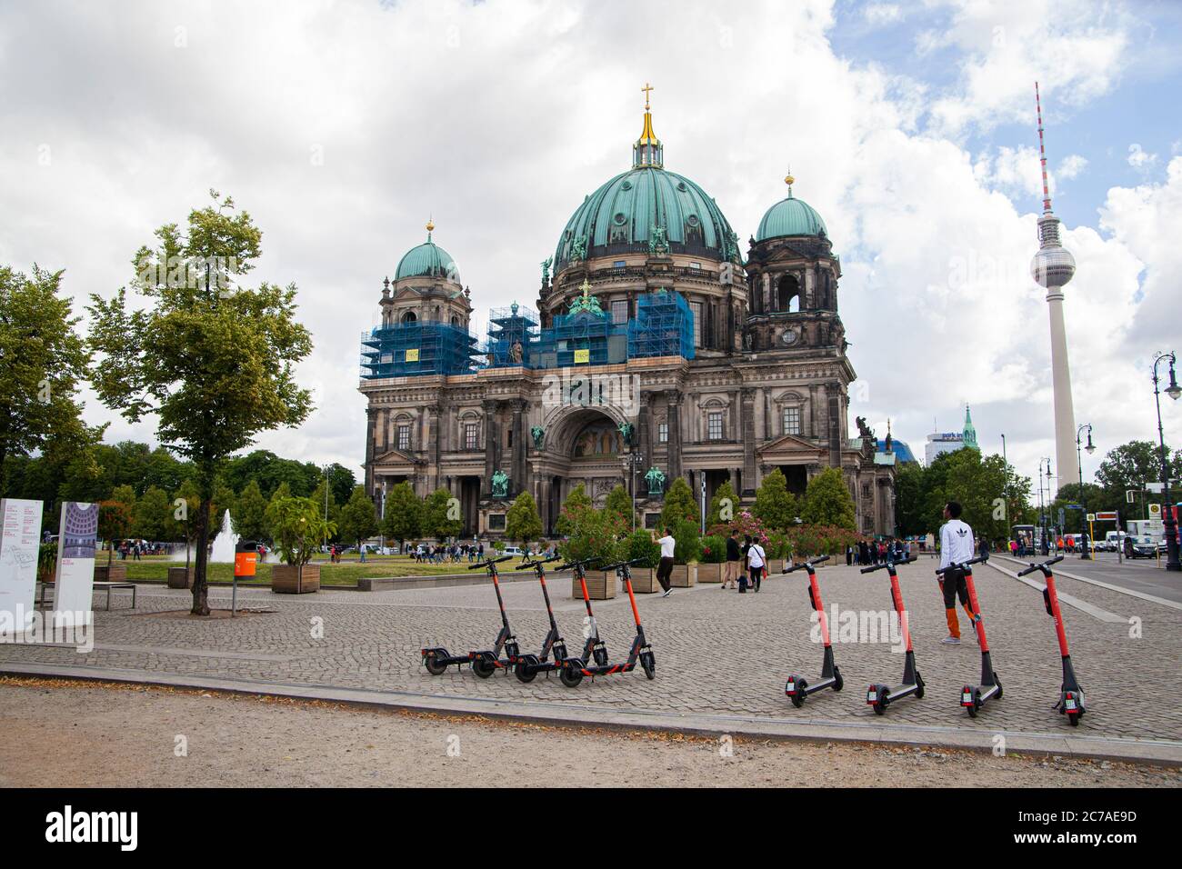 Una Cattedrale di Berlino con una torre televisiva sullo sfondo e una linea di scooter elettrici in primo piano Foto Stock