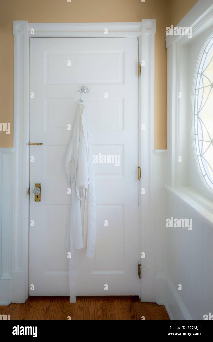 Accappatoio appeso sul retro della porta del bagno con un'atmosfera morbida e soffusa Foto Stock