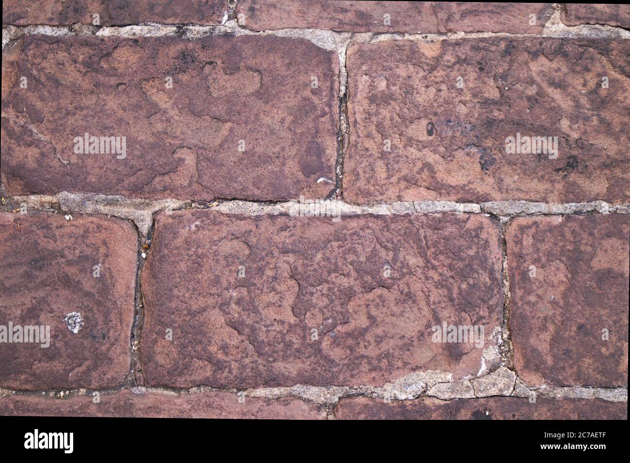 Terra acciottolata con blocchi di pietra di colore rossastro di rodeno forma uno sfondo testurizzato Foto Stock