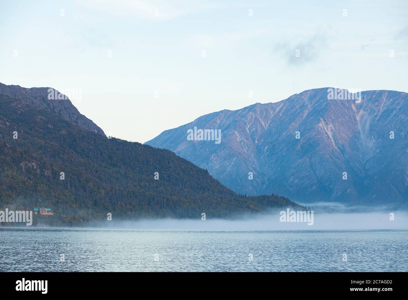 Le acque calme di un lago dell'Alaska riflettono montagne coperte di nuvole, che mostrano la bellezza incontaminata e la serenità del paesaggio selvaggio. Foto Stock