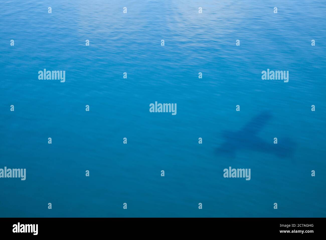 L'ombra di un idrovolante si riflette sulle calme acque blu sottostanti, catturando l'essenza del viaggio nella natura selvaggia nella remota Alaska Foto Stock