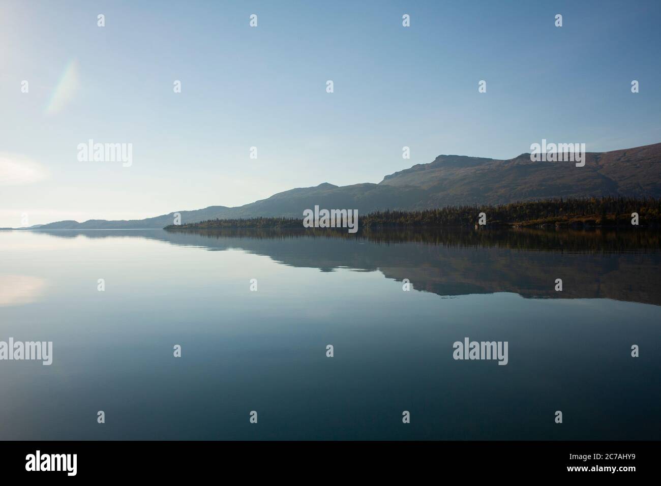 Lago incontaminato dell'Alaska con acque calme e riflettenti che rispecchiano aspre montagne sotto un cielo limpido, catturando la serenità incontaminata della natura selvaggia. Foto Stock