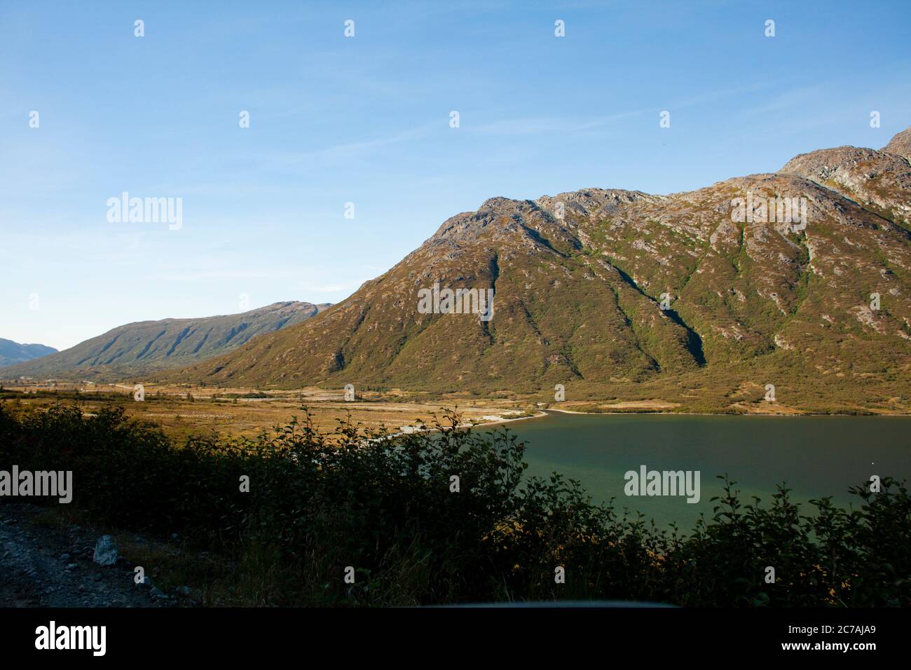 Una valle serena in Alaska con un lago calmo incastonato tra aspre montagne, che mostra la bellezza incontaminata e la tranquillità della natura selvaggia. Foto Stock