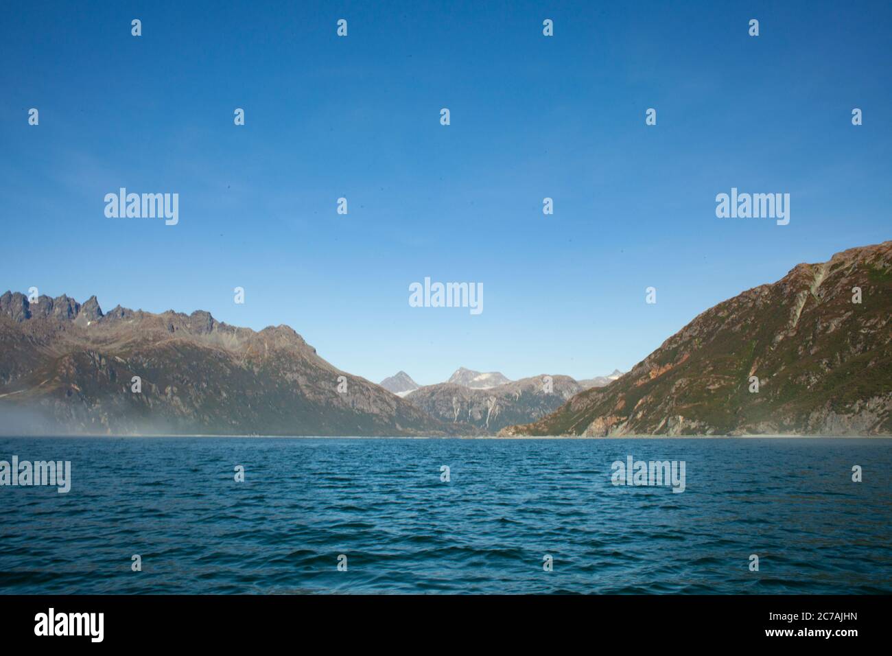 La nebbia si snoda sulle acque del lago Iliamna, Alaska, con il sole che getta luce sull'aspra silhouette di montagna e sul tranquillo paesaggio selvaggio Foto Stock