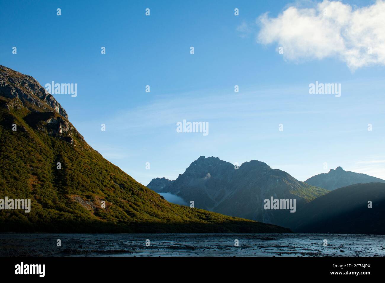 Aspre montagne in Alaska con nebbia che si snoda sulle pendici, catturando la bellezza serena e la spettacolare natura selvaggia del paesaggio remoto del lago Iliamna. Foto Stock