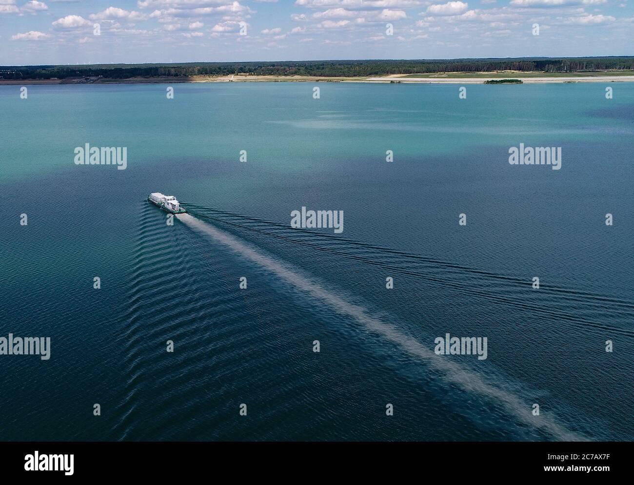 14 luglio 2020, Brandenburg, Sedlitz: Il serbatoio di trattamento delle acque Klara della Lausitzer und Mitteldeutsche Bergbau-Verwaltungsgesellschaft mbH (LMBV) sta diffondendo calce viva nelle acque del lago di Sedlitz per migliorare la qualità dell'acqua (foto aerea con un drone). La miniera a cielo aperto di Sedlitz è stata limata per conto della LMBV da giugno. Questa prima neutralizzazione viene effettuata con il proprio serbatoio di trattamento delle acque della LMBV Klara, già in funzione sul lago Partwitz. La misura dovrebbe essere effettuata entro la fine di settembre. Circa 10,000 tonnellate di cosiddetto quicklim Foto Stock