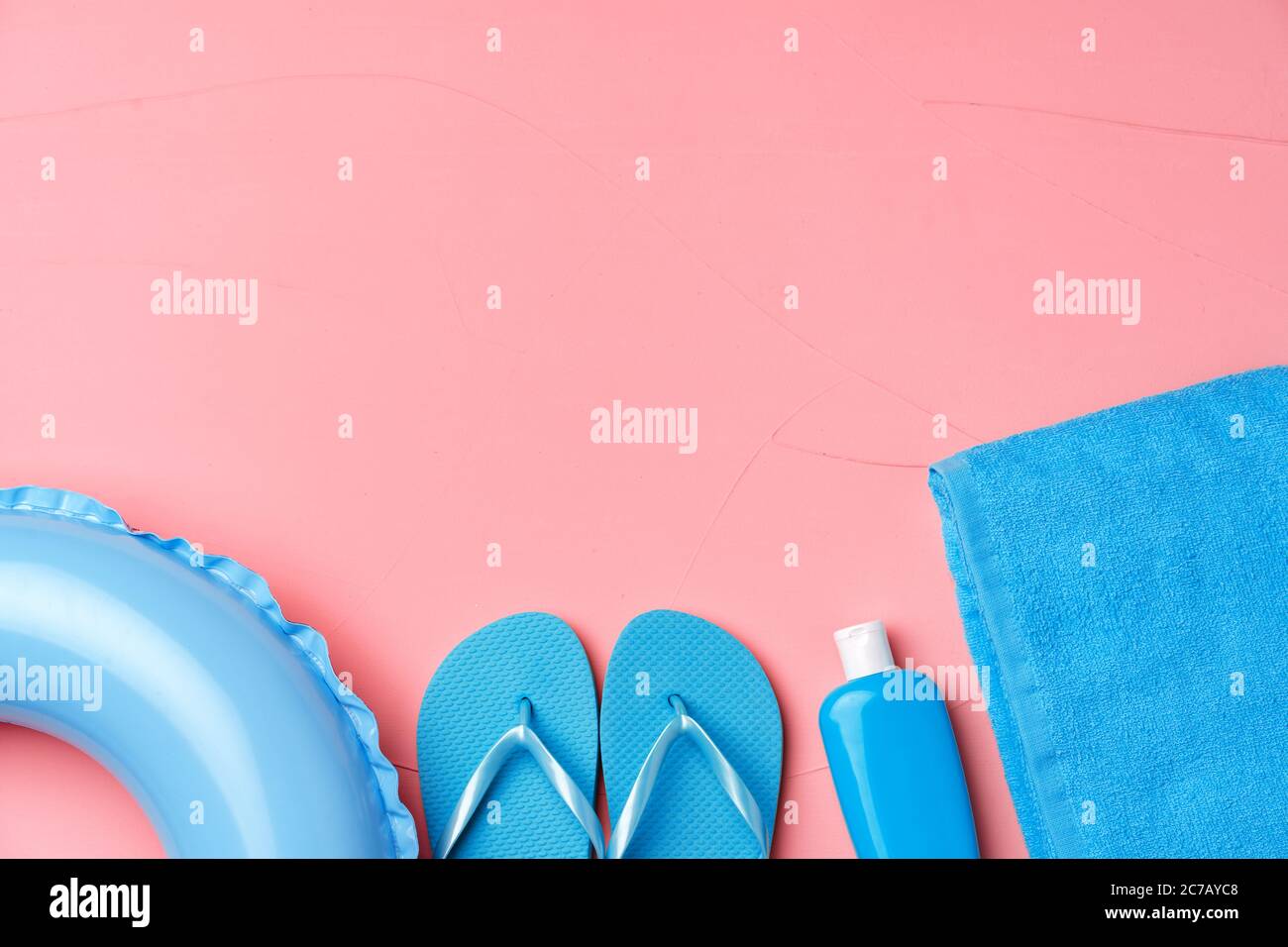 Concetto di spiaggia con anello di gomma blu, asciugamano, infradito e idrodivatore su sfondo rosa Foto Stock