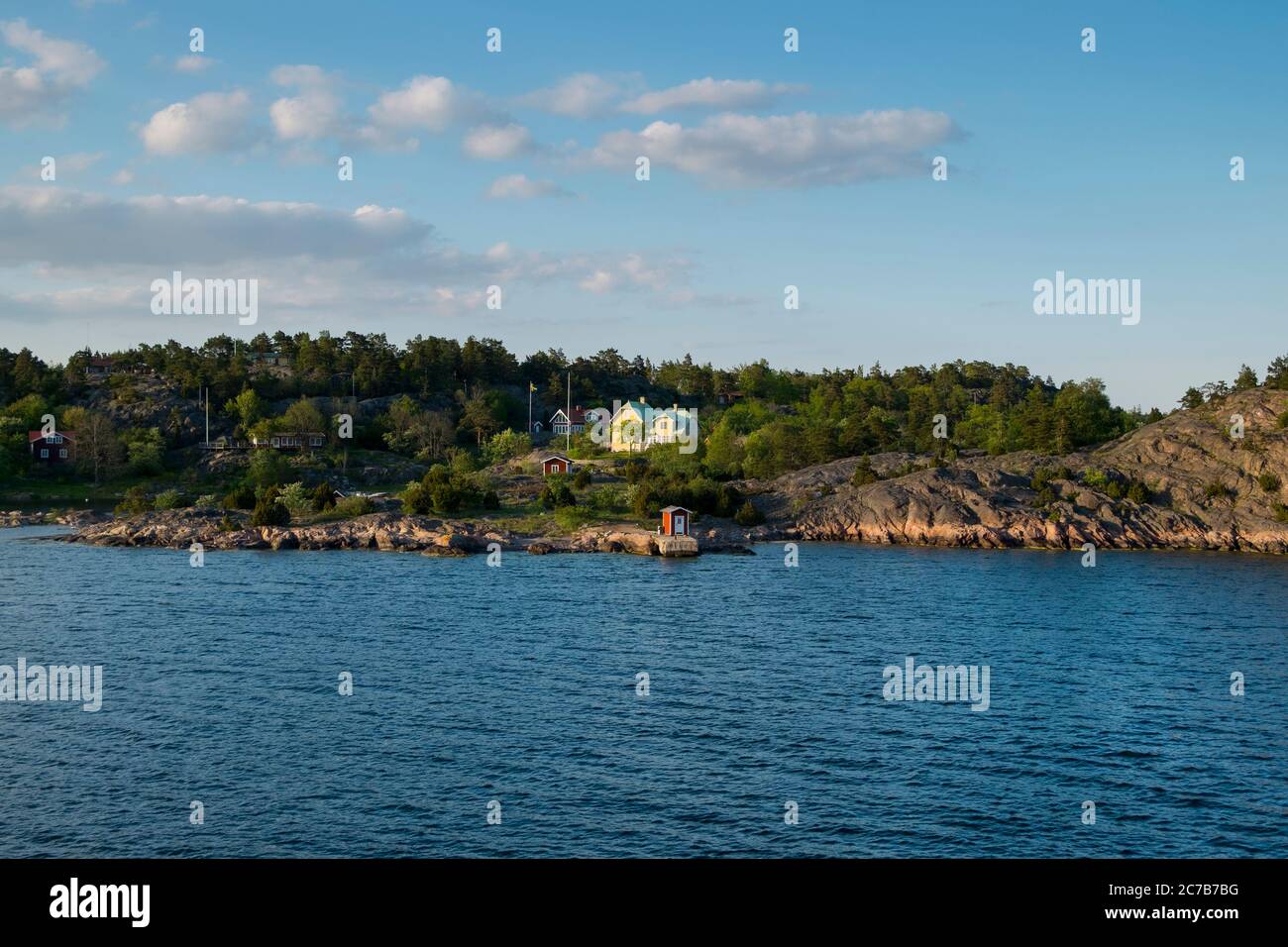 Una piccola banchina rossa si trova sulla costa durante il tramonto dorato nel tardo pomeriggio. Crociera sul lago Mälaren vicino a Stoccolma, Svezia. Foto Stock