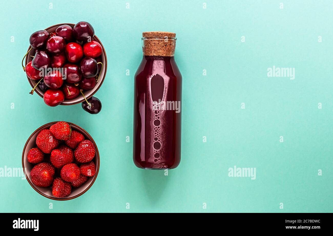Succo di bacche fredde in una bottiglia di vetro con bacche mature Foto Stock