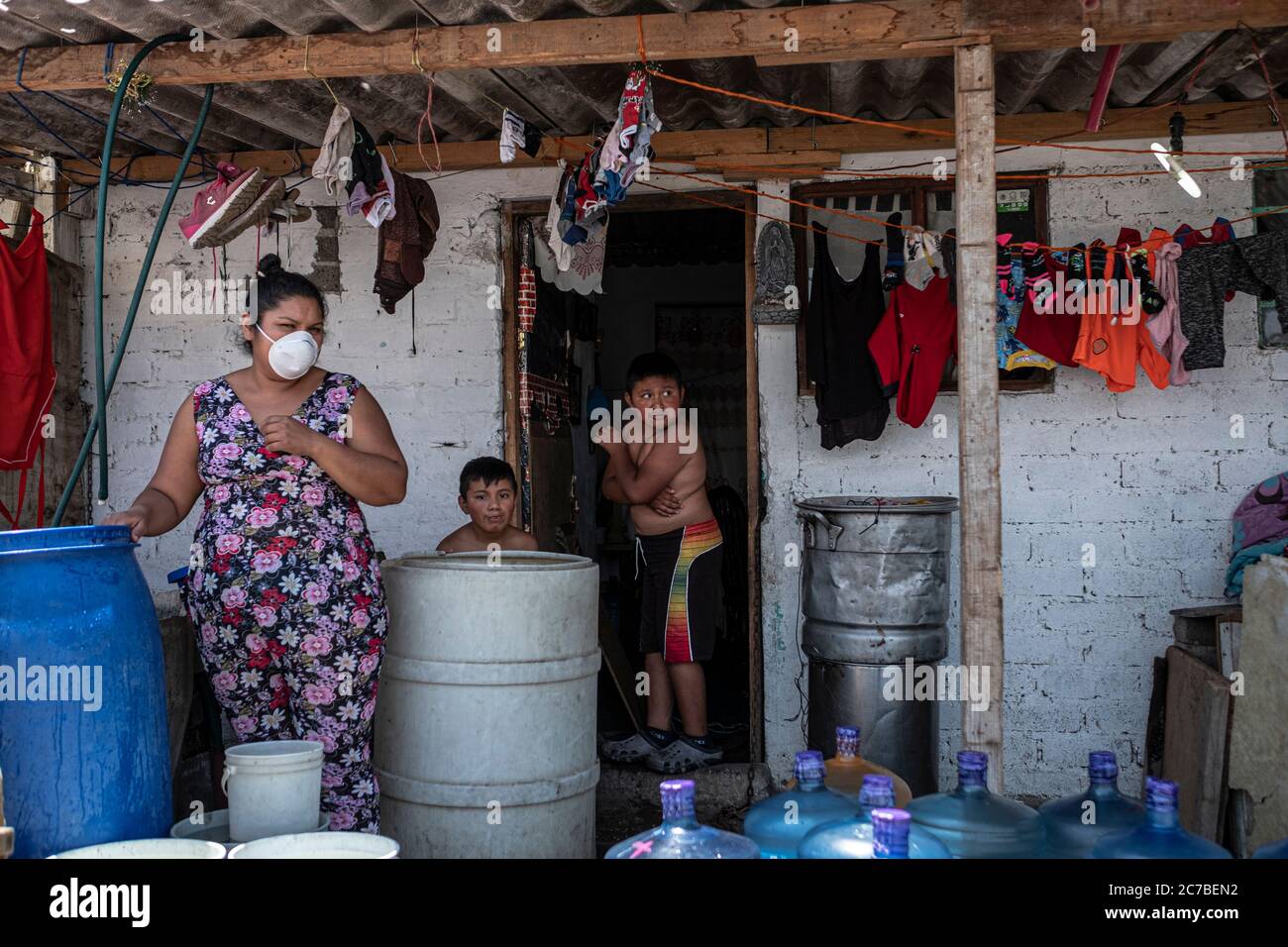 Mexiko Stadt, Messico. 15 luglio 2020. Una famiglia sta in piedi fuori della loro casa. Molte famiglie attualmente soffrono di una carenza di acqua potabile. Il Messico è ora il paese con la quarta morte più registrata per malattia polmonare di Covid-19. Credit: Jacky Muniello/dpa/Alamy Live News Foto Stock