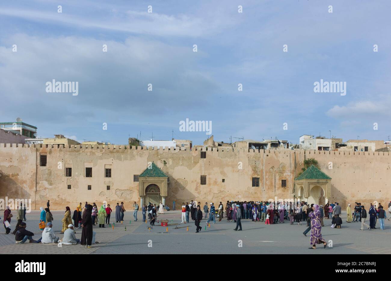 Nel pomeriggio a Meknes, Marocco, gente marocchina che cammina sulla piazza vicino alle mura della città. Cielo blu Foto Stock