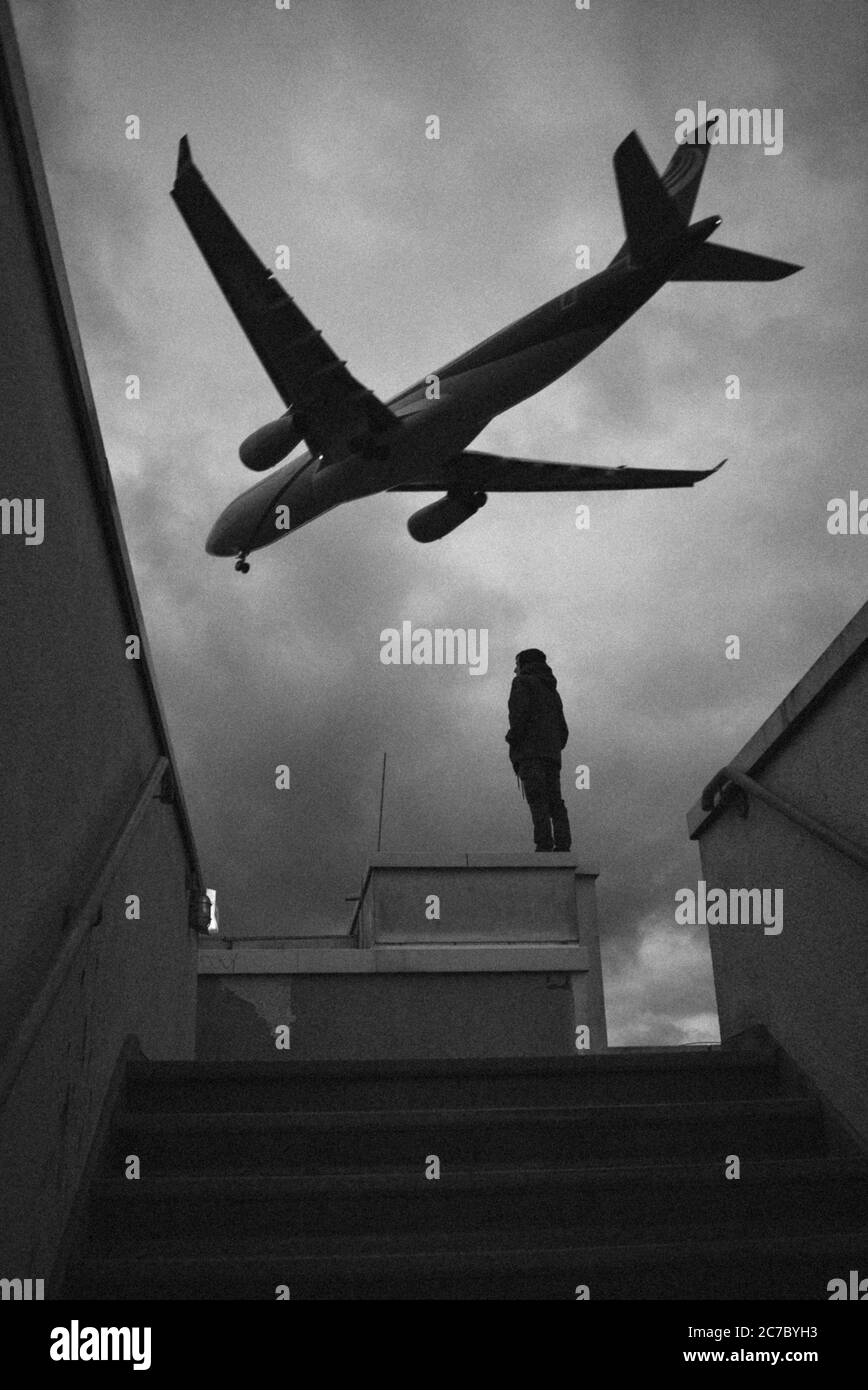 Immagine verticale in scala di grigi di un aereo che sorvola Berlino, Germania Foto Stock