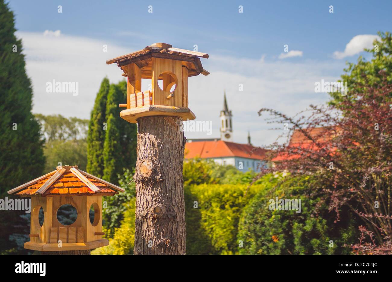 alimentatore di uccelli in legno nel giardino, sullo sfondo la torre del castello Foto Stock