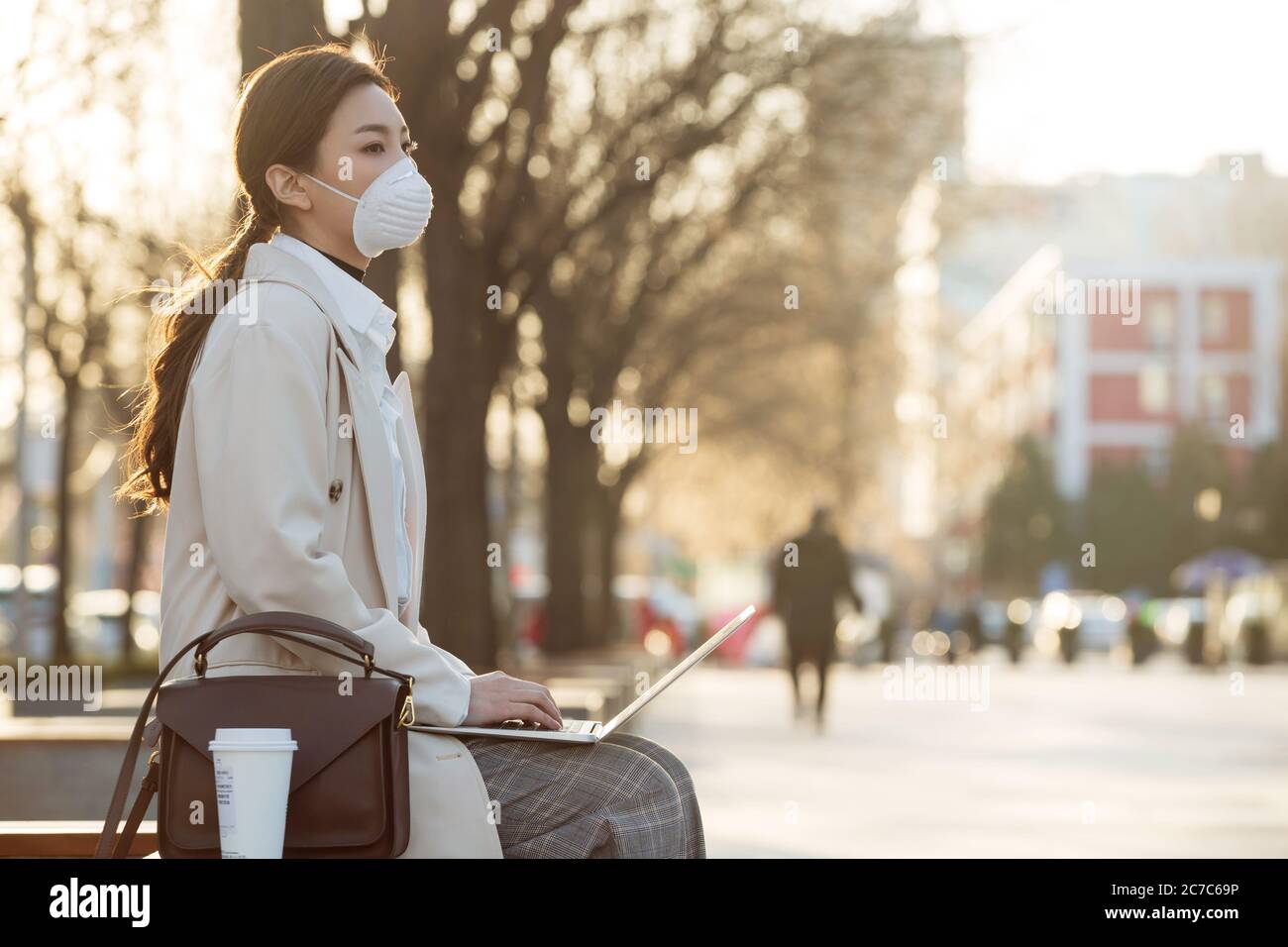 Indossare una maschera di donna di affari in esterno utilizzare il computer Foto Stock