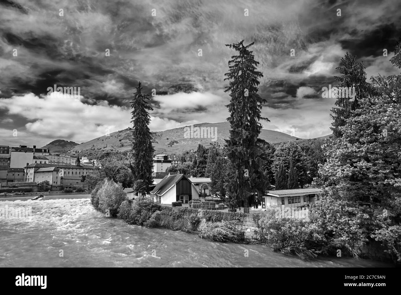 Alberi di abete rosso sulla riva di un fiume di montagna veloce. Situato a Lourdes, il dipartimento degli alti Pirenei nella regione dell'Occitanie, a sud-ovest Foto Stock