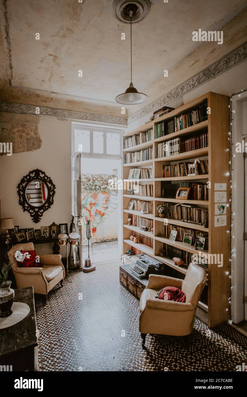 Immagine verticale dell'interno di una stanza d'epoca con una libreria e poltrone bianche Foto Stock