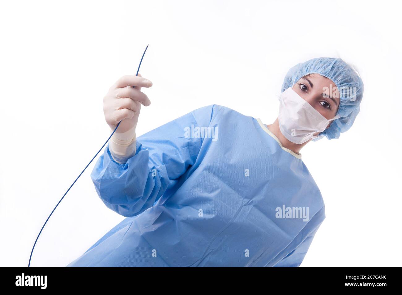 Medico o infermiere di sesso femminile che indossa una tuta o un abito sterile blu che tiene un catetere per l'ablazione per una procedura cardiaca. Foto Stock