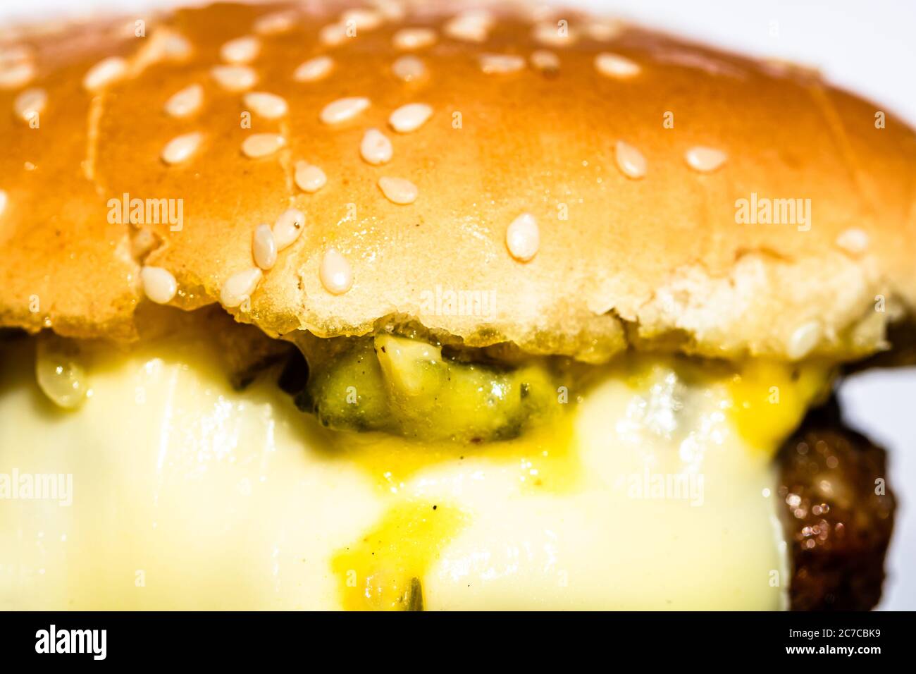 Primo piano di formaggio fuso in un cheeseburger fatto in casa isolato su piatto nero. Foto Stock