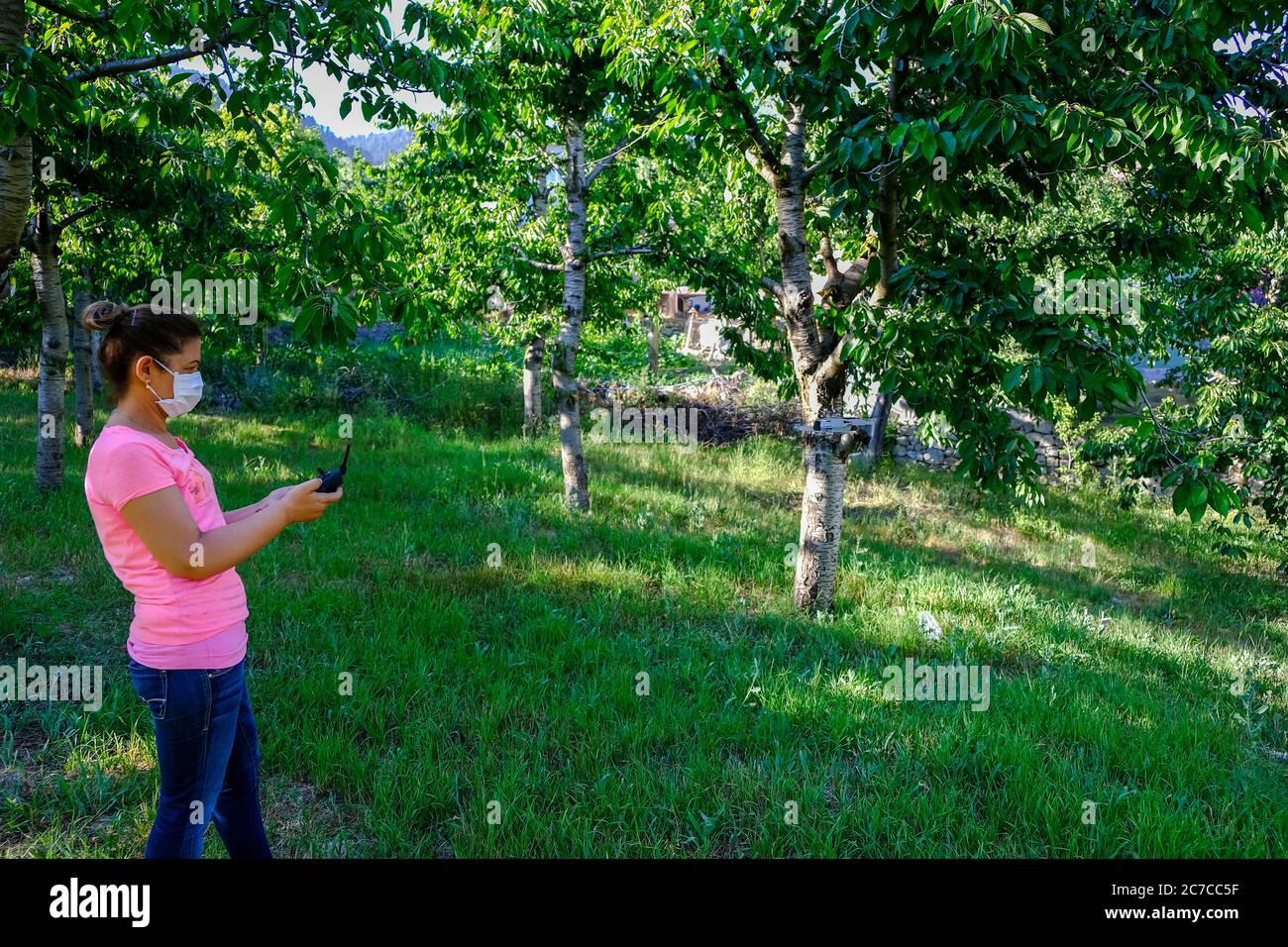 Donna che vola drone in natura in nuova vita normale. Donna che si diverte nel parco con maschera a causa del virus corona. Foto Stock