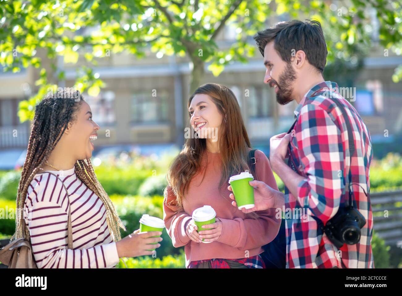 Ragazza mulatto con ragazza e ragazzo in piedi in piazza con caffè Foto Stock