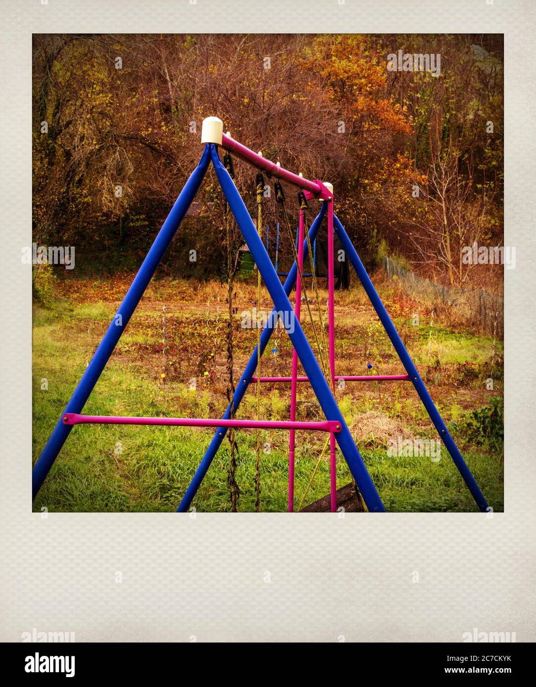 Effetto Polaroid . Variopinta altalena in un tranquillo parco circondato da foglie autunnali nel tardo pomeriggio, in Francia Foto Stock