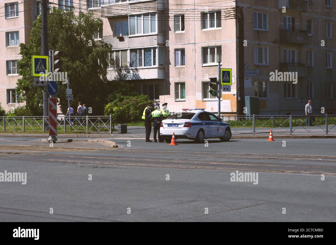 San Pietroburgo, Russia - 12 giugno 2020: Pattuglia stradale di tre agenti di polizia in maschere mediche accanto a una macchina di polizia Foto Stock